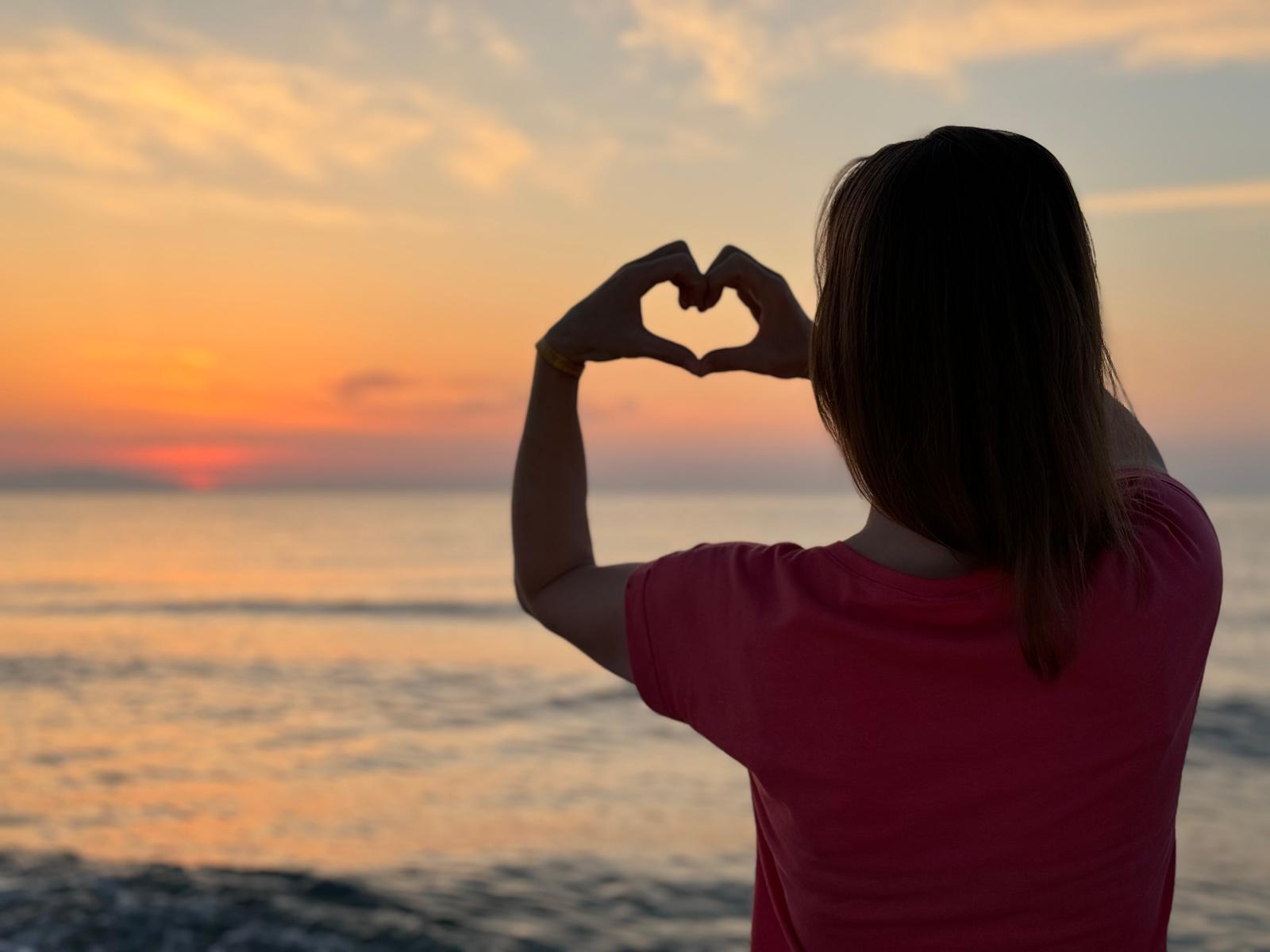 Herz geformt aus Händen im Sonnenaufgang