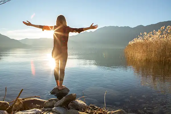 Frau am See mit offenen Armen